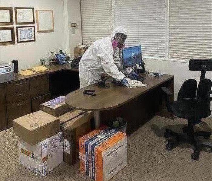 Technician wearing full PPE's wiping down a desk