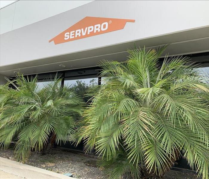 A Large white building with an orange SERVPRO logo against a grey sky.