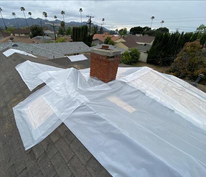 Roof top damaged by house fire with wood and white plastic before adding a blue tarp to prevent more damages 